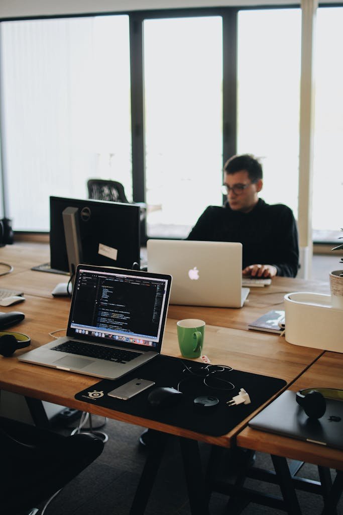 Photo by Djordje Petrovic A web developer working on code in a modern office setting with multiple devices.
